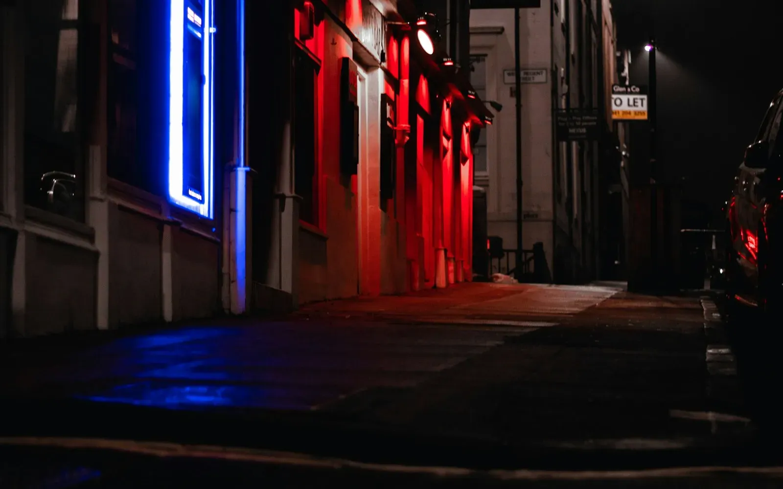 Nächtliche Gasse mit rotem und blauem Neonlicht – Laufhaus, Bordell und Escort im Unterschied