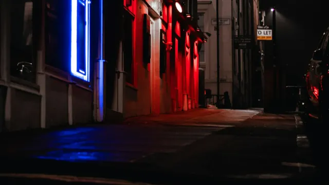 Nächtliche Gasse mit rotem und blauem Neonlicht – Laufhaus, Bordell und Escort im Unterschied